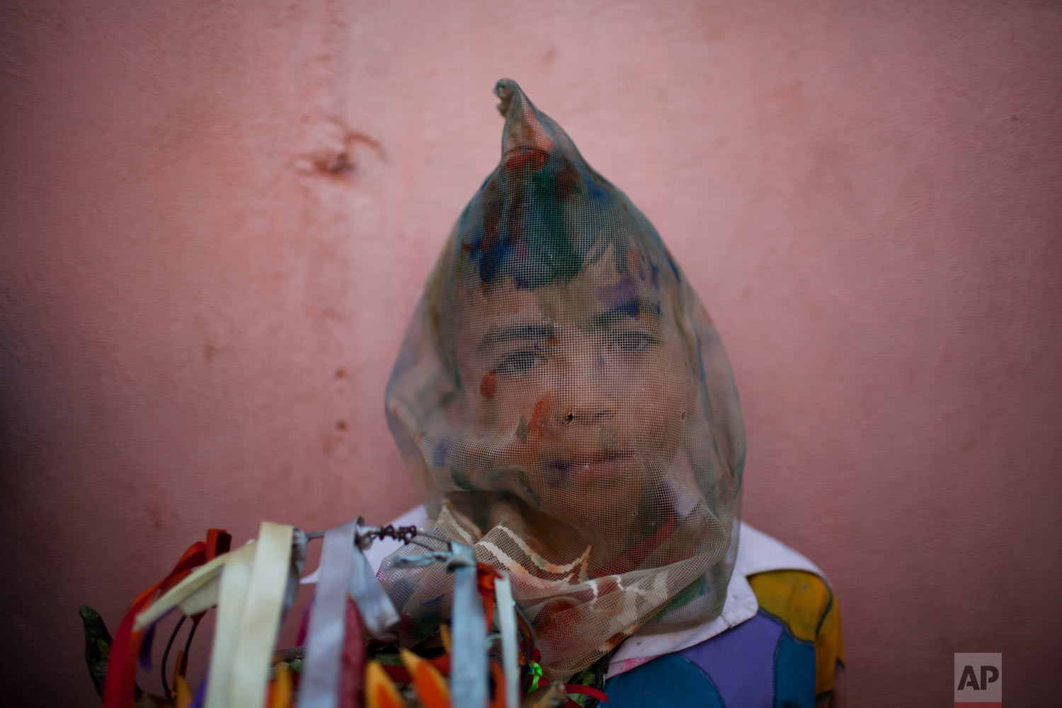 A boy dressed as dancing devil stands against a wall during a traditional celebration in Naiguata, Venezuela, Thursday, May 31, 2018. Carrying in their hands striking masks mostly animals and sea monsters, hundreds of men, women and children went out to dance frantically as possessed by evil spirits in an ancient ritual known as Dancing Devils of Naiguata, the unorthodox way of the coastal towns of Venezuela to venerate God during the celebrations of Corpus Christi. (AP Photo/Ariana Cubillos)