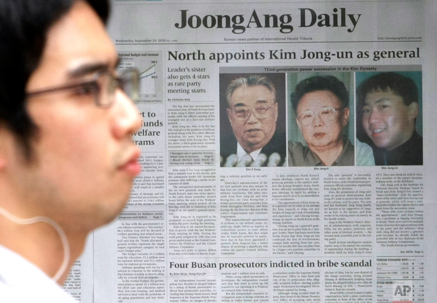 A man walks past a South Korean newspaper bearing photos of North Korean leader Kim Jong Il, center, his late father Kim Il Sung, left, and his youngest son Kim Jong Un, in Seoul, South Korea, on Sept. 29, 2010. (AP Photo/Ahn Young-joon)