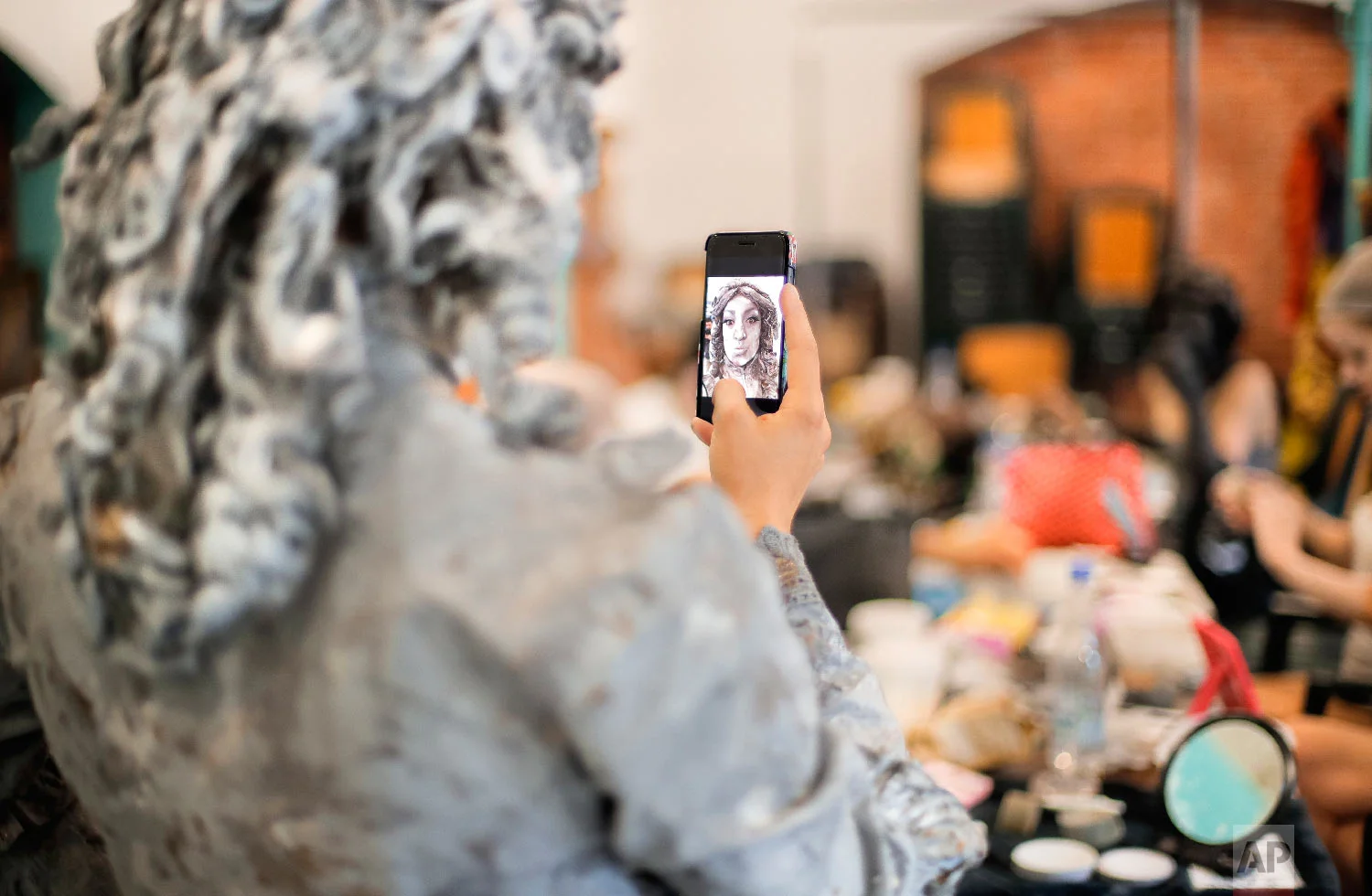 An artist of The Netherlands' Levend Theater takes a selfie before performing her Angel character during the Living Statues International Festival, in Bucharest, Romania on Tuesday, May 22, 2018. (AP Photo/Vadim Ghirda)