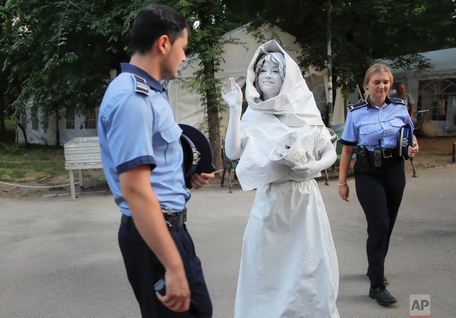 An artist of Ukraine's Artel Myth, walks by Romanian police officers, in Bucharest, May 24, 2018. (AP Photo/Vadim Ghirda)