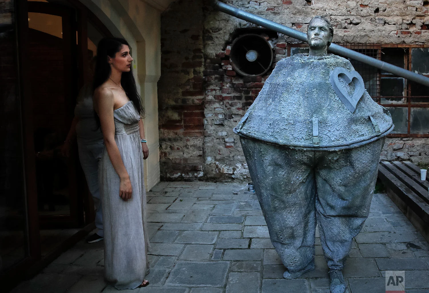 A woman looks at an artist of Romania's Masca theatre waiting to perform at the Living Statues International Festival, in Bucharest, Romania on May 22, 2018. (AP Photo/Vadim Ghirda)