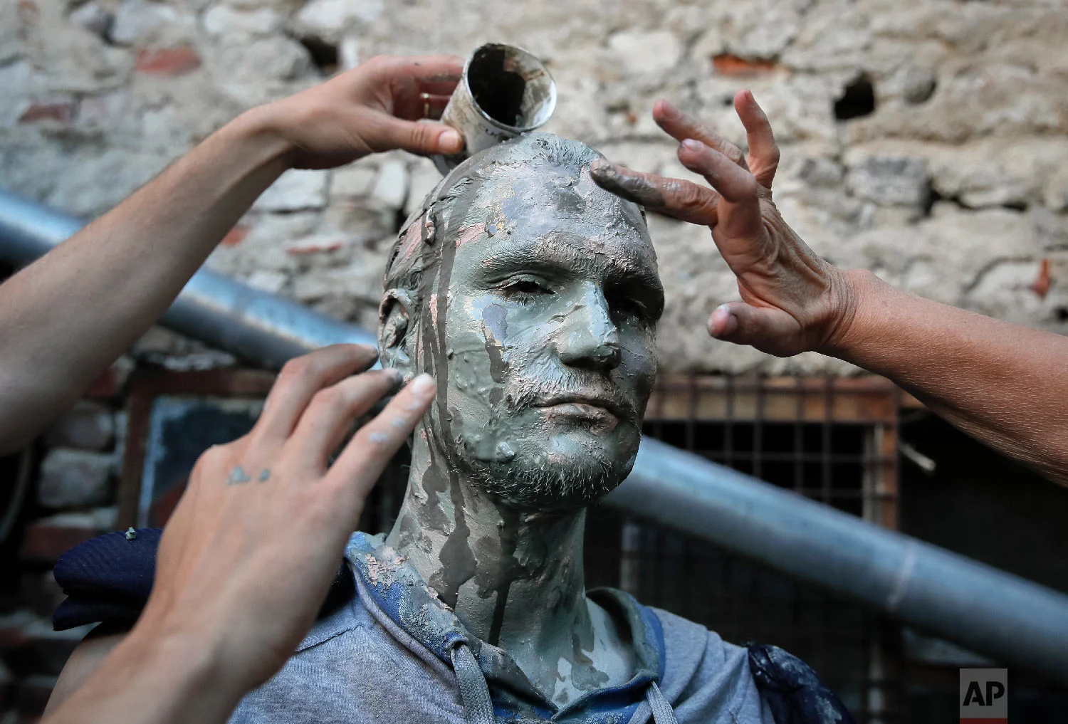 An artist of Romania's Masca theatre has make-up applied to his face before performing at the Living Statues International Festival, in Bucharest, Romania on Tuesday, May 22, 2018,. (AP Photo/Vadim Ghirda)