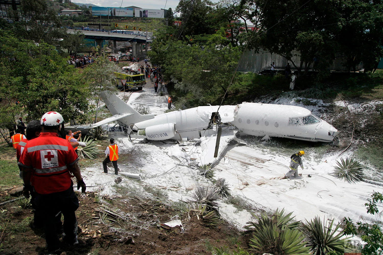 A white Gulfstream jet lies broken in half and engulfed in foam sprayed by firefighters, in Tegucigalpa, Honduras, Tuesday, May 22, 2018. The private jet crashed off the end of the runway, but the crew and passengers were rescued and out of danger, according to Honduras emergency management agency. (AP Photo/Fernando Antonio)