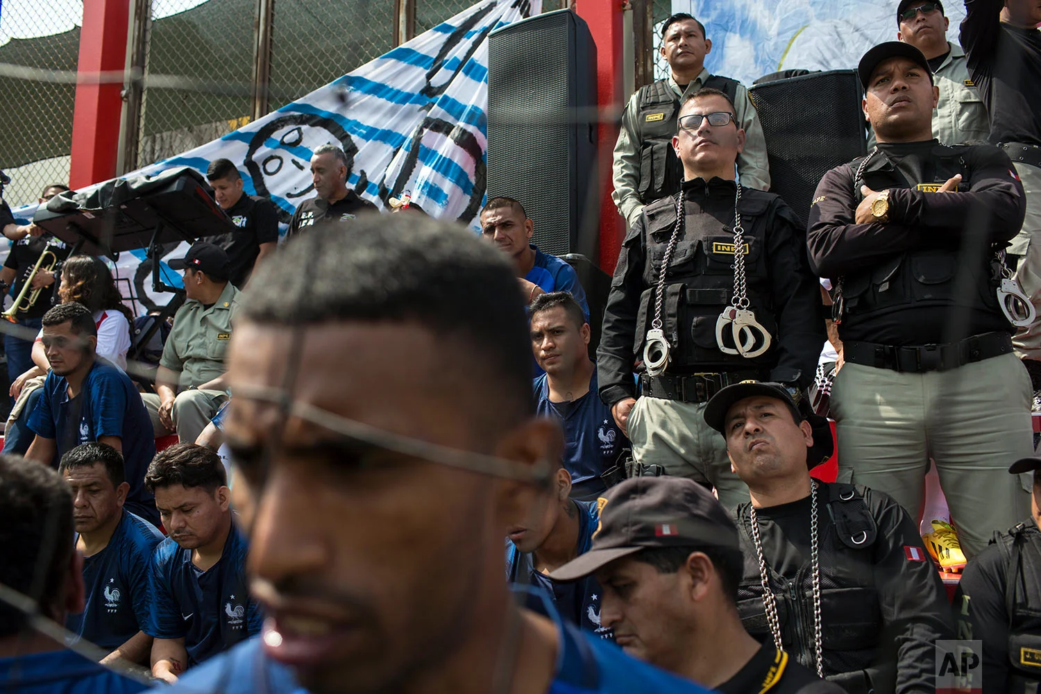 Inmates escorted by prison guards watch a soccer match in the San Juan de Lurigancho prison, in Lima, Peru, Thursday, May 24, 2018. Inmates of 17 prisons, including four for women, participated in the First Interprison World Cup Lima 2018, organized by the National Penitentiary Institute. (AP Photo/Rodrigo Abd)