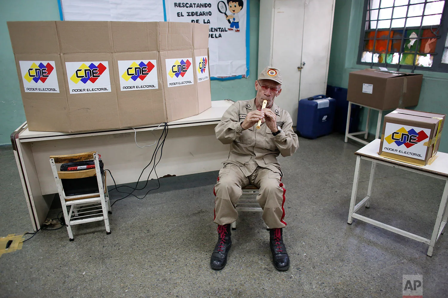 A Bolivarian Militia member plays the flute at a polling station during the presidential election in Caracas, Venezuela, Sunday, May 20, 2018. Before the government-controlled National Election Council declared current President Nicolas Maduro the overwhelming winner, nations around the world had accused him of taking Venezuela down the path toward "dictatorship." (AP Photo/Ariana Cubillos)