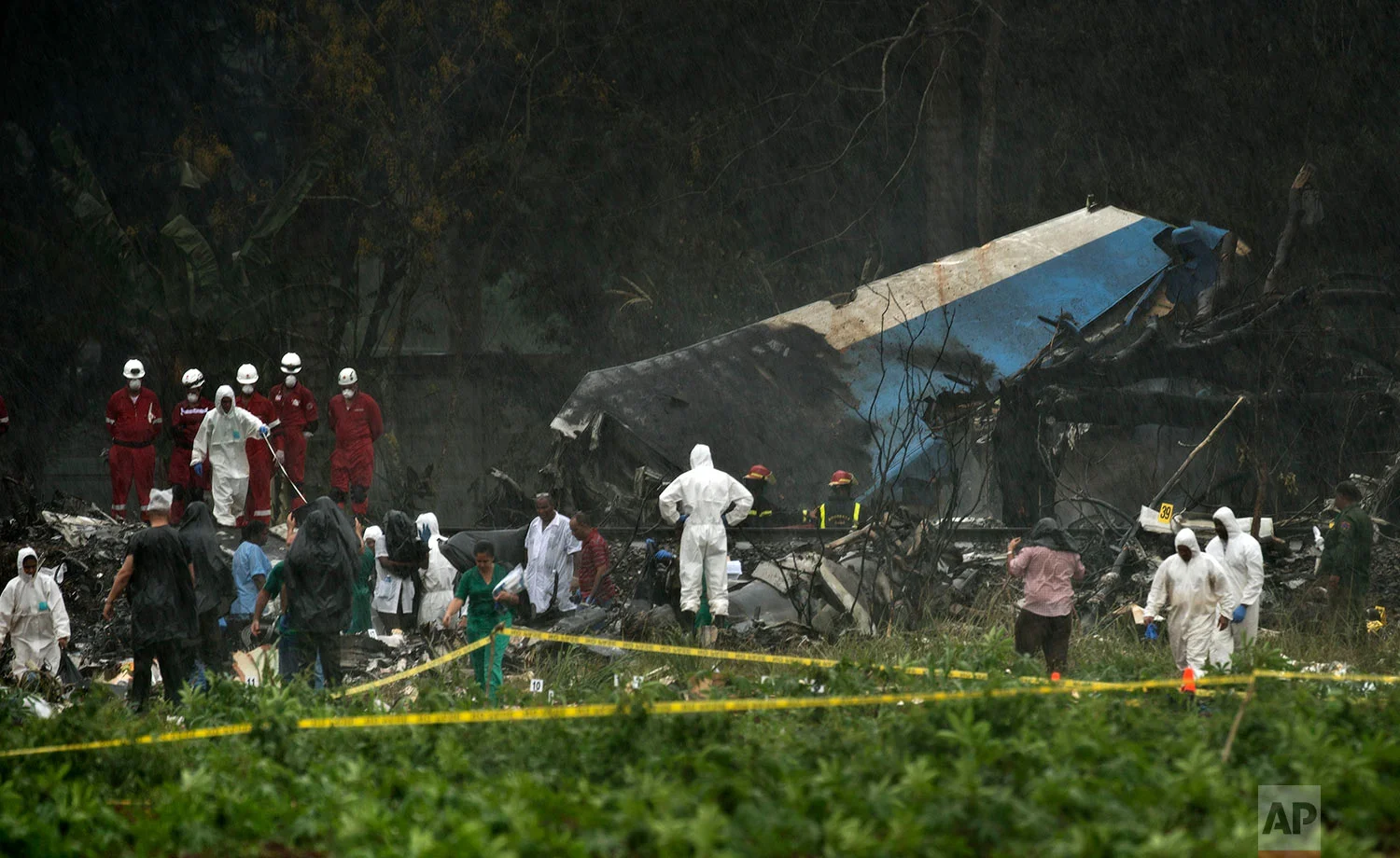 Rescue teams search the wreckage site of a Boeing 737 that plummeted into a cassava field with more than 100 passengers on board in Havana, Cuba, Friday, May 18, 2018. The Cuban airliner crashed just after takeoff from Havana's international airport in Havana, Cuba. (AP Photo/Ramon Espinosa)
