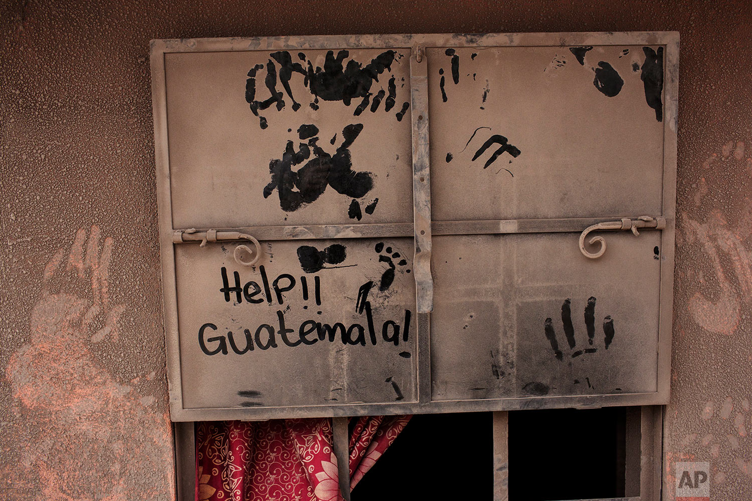 The front door of a home blanketed in volcanic ash carries a hand written help sign in the disaster zone near the Volcan de Fuego, or "Volcano of Fire," in the El Rodeo hamlet of Escuintla, Guatemala, Tuesday, June 5, 2018. (AP Photo/Rodrigo Abd)