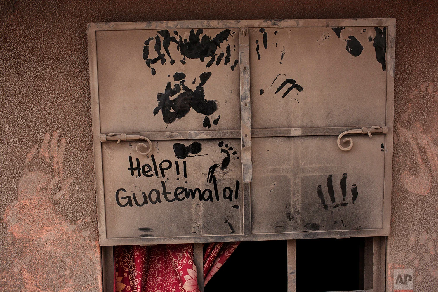 The front door of a home blanketed in volcanic ash carries a hand written help sign in the disaster zone near the Volcan de Fuego, or "Volcano of Fire," in the El Rodeo hamlet of Escuintla, Guatemala, Tuesday, June 5, 2018. (AP Photo/Rodrigo Abd)