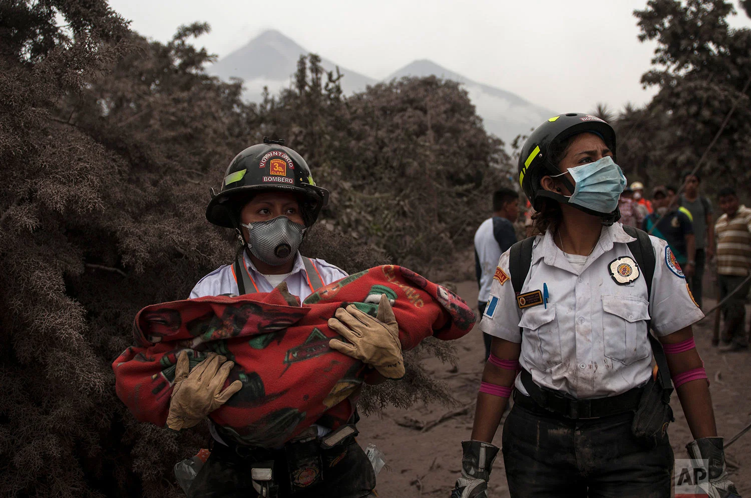 A firefighter carries the body of a child recovered near the Volcan de Fuego, which means in Spanish Volcano of Fire, in Escuintla, Guatemala, Monday, June 4, 2018. (AP Photo/Oliver de Ros) 