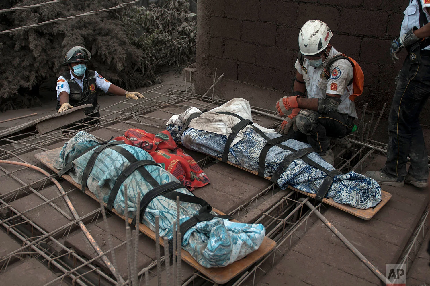 A firefighter kneels besides bodies recovered near the Volcan de Fuego, or "Volcano of Fire," in Escuintla, Guatemala, Monday, June 4, 2018. The fiery volcanic eruption in south-central. (AP Photo/Oliver de Ros)
