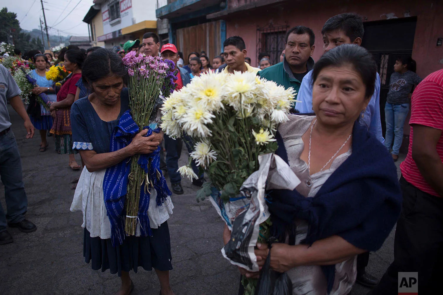 Women carry flowers during the funeral procession for seven people who died during the eruption of the Volcan de Fuego, which in Spanish means Volcano of Fire, as they make their way to the cemetery in San Juan Alotenango, Guatemala, Monday, June 4, 2018. Residents of villages skirting the volcano began mourning the dead after an eruption buried them in searing ash and mud. (AP Photo/Luis Soto)