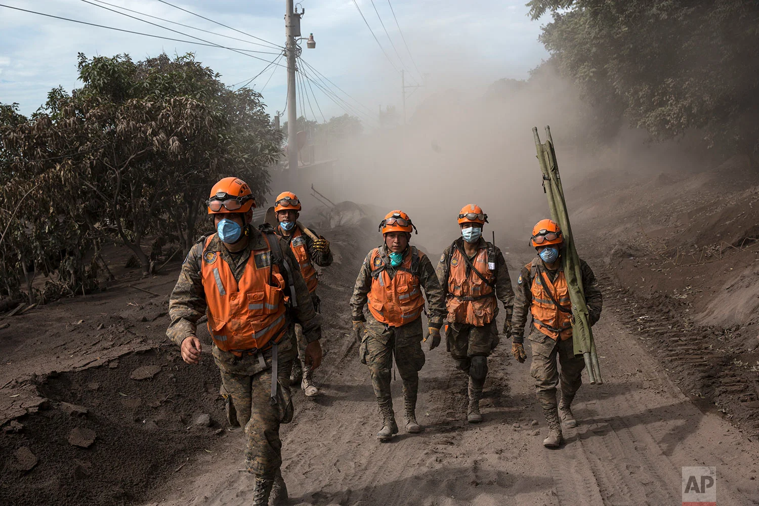 Rescue worker walk near the Volcan de Fuego, or "Volcano of Fire," in El Rodeo, Guatemala, Wednesday, June 6, 2018. Rescuers were concerned about possible dangers posed not only by more volcanic flows but also rain. Authorities have said the window is closing on the chances of finding anyone else alive in the devastation. (AP Photo/Rodrigo Abd)