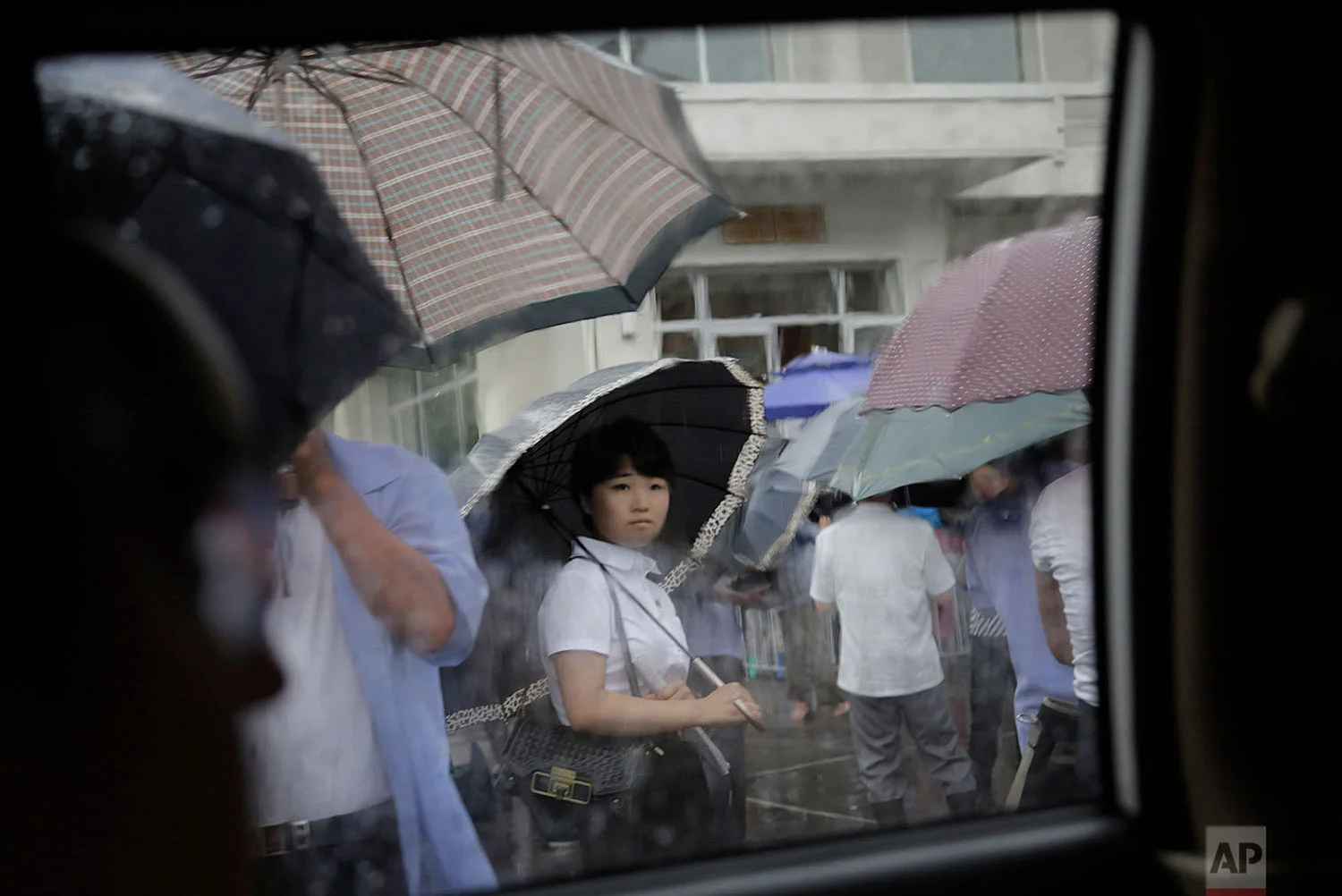 A woman waits in the rain outside a restaurant in Pyongyang, North Korea, on July 25, 2015. The rainy season in North Korea usually lasts through the month of July. (AP Photo/Wong Maye-E)
