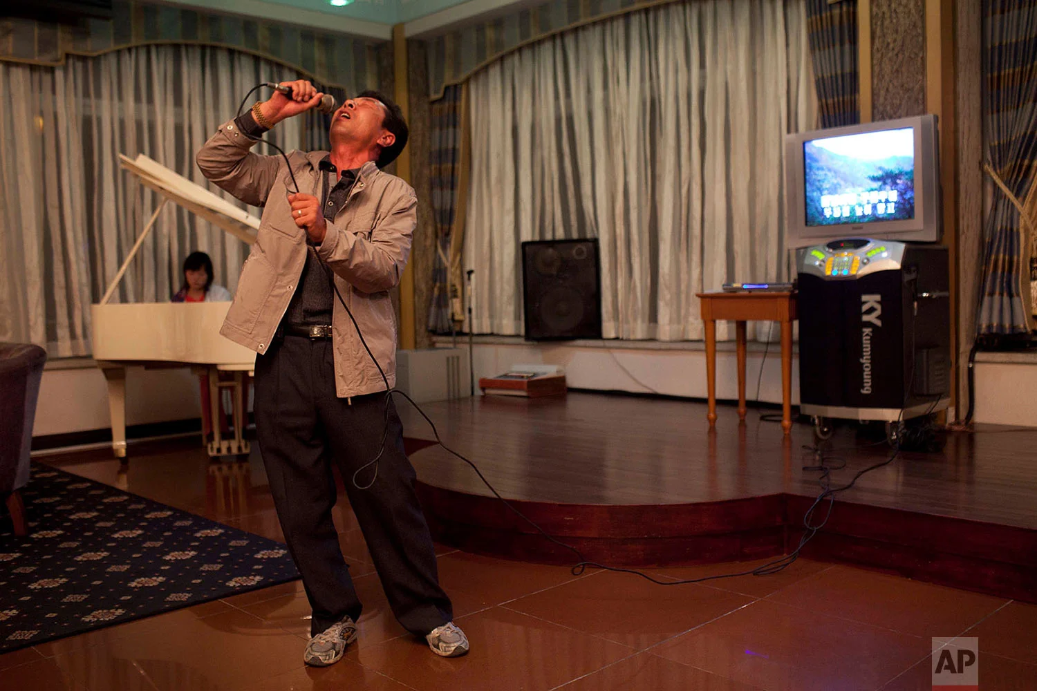 A man sings karaoke while his daughter plays piano at a hotel bar in Mount Kumgang, North Korea, on Oct. 7, 2011. (AP Photo/David Guttenfelder)