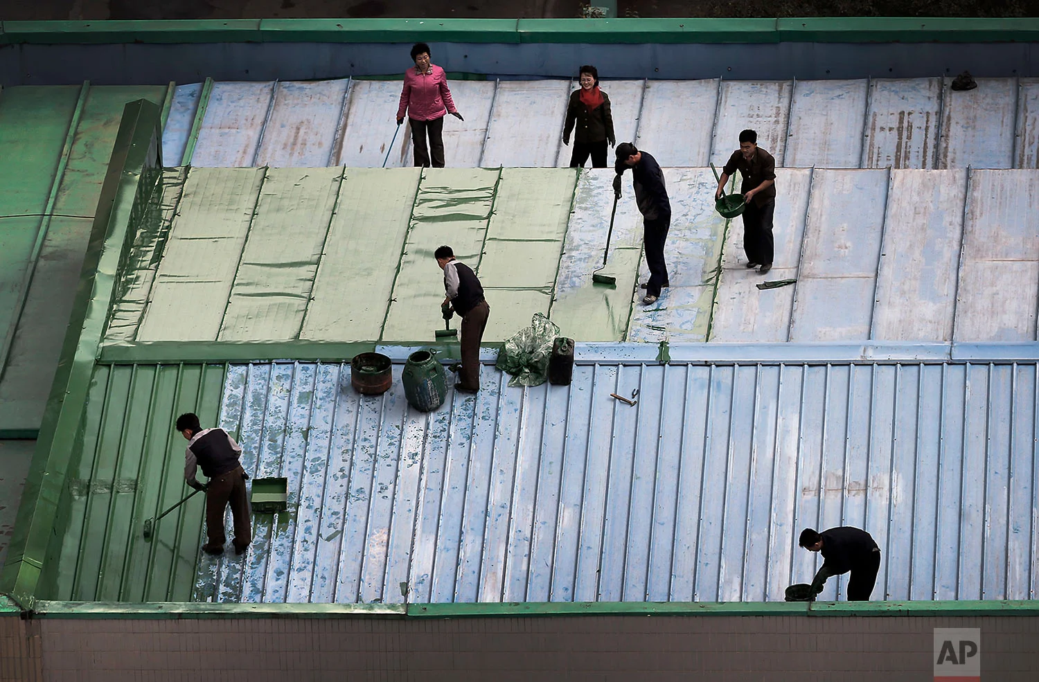 Men and woman paint the roof of a restaurant in downtown Pyongyang, North Korea, on Oct. 25, 2014. (AP Photo/Wong Maye-E)