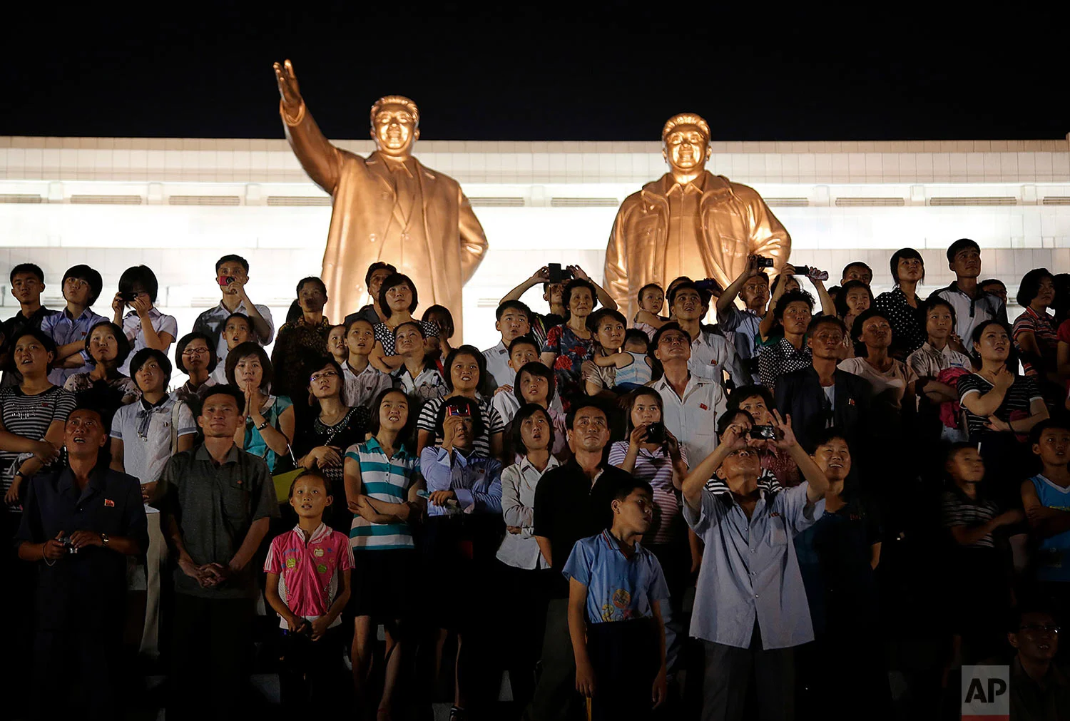 The bronze statues of late North Korean leaders Kim Il Sung and Kim Jong Il tower over people in Pyongyang as they watch fireworks explode on July 27, 2015, during a celebration of the 62nd anniversary of the armistice that halted the Korean War. (AP Photo/Wong Maye-E)