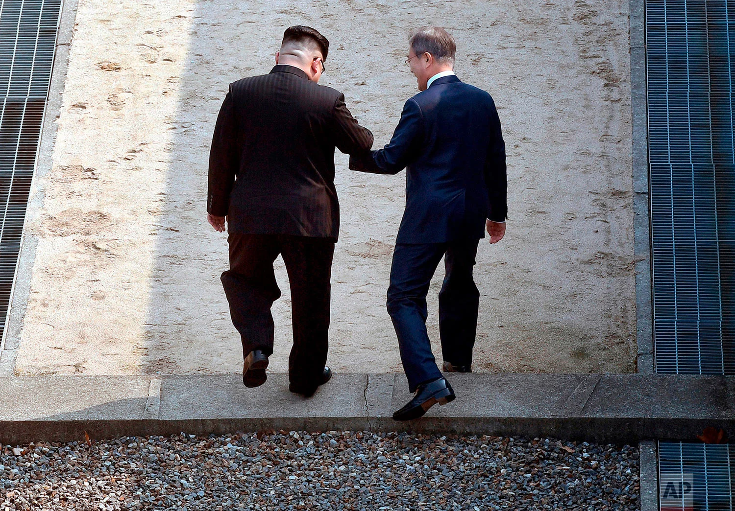 North Korean leader Kim Jong Un, left, and South Korean President Moon Jae-in cross the military demarcation line at the border village of Panmunjom in the Demilitarized Zone that divides the North and South on April 27, 2018. (Korea Summit Press Pool via AP)
