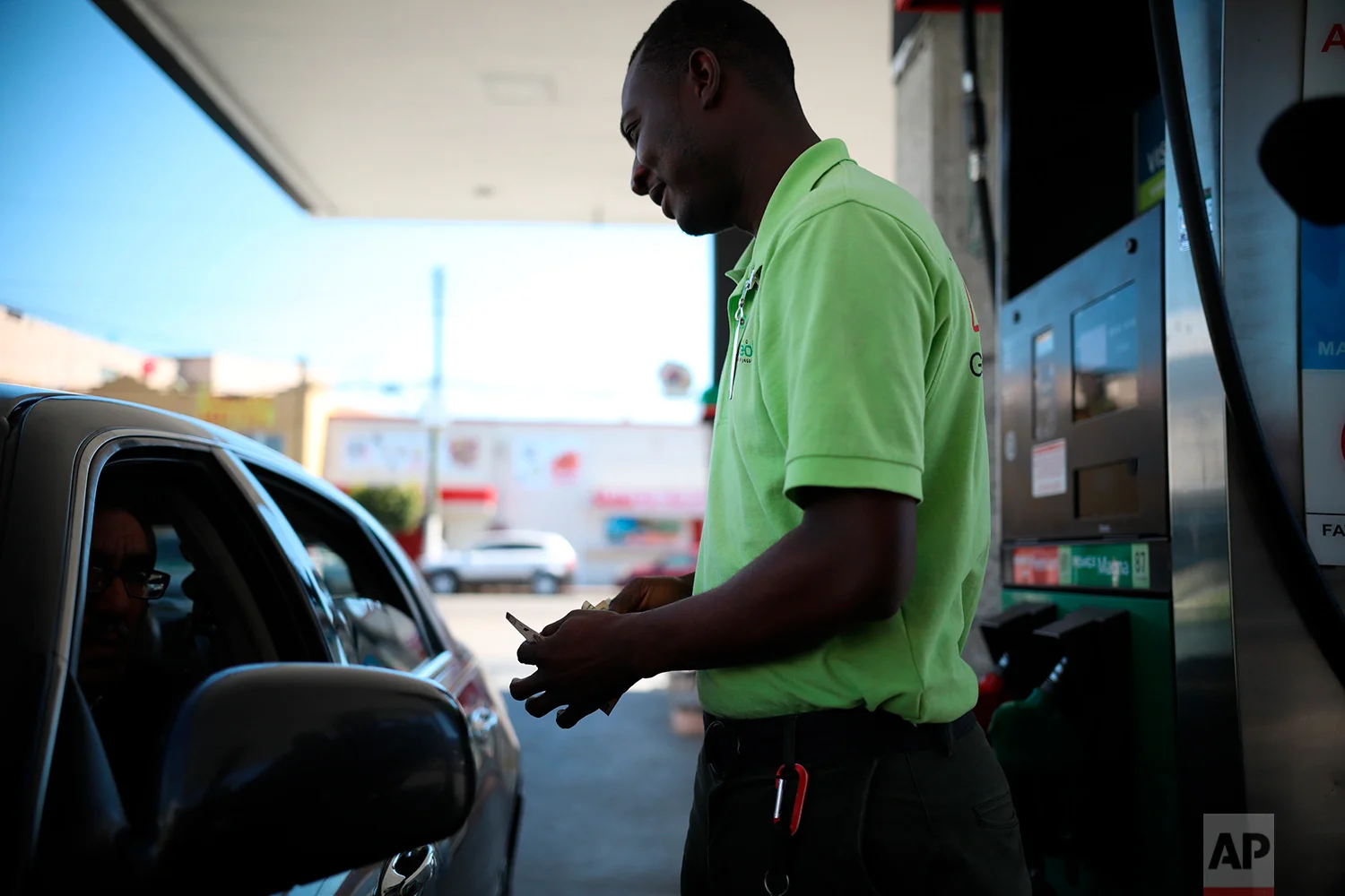Herllain Gamin, a Haitian migrant, counts his change at the gas station where he works in downtown Tijuana, Mexico, May 4, 2018. When he first arrived, Gamin said that he experienced racist attitudes from Mexicans, but now says he and others are accepted and welcomed by most. (AP Photo/Emilio Espejel)