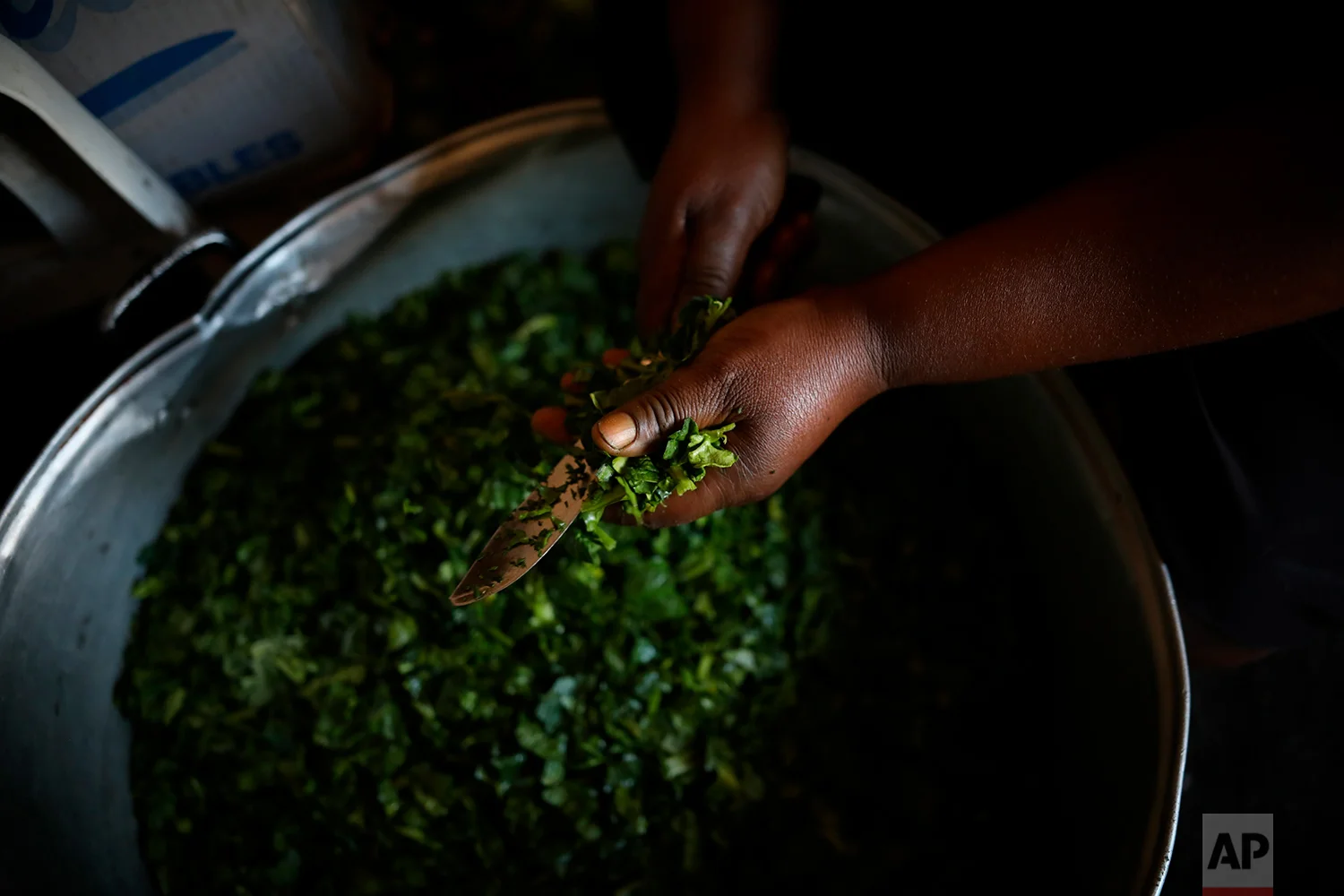 Rosaline, a Haitian migrant, cuts spinach for a dish at her restaurant in downtown Tijuana, Mexico, May 4, 2018. (AP Photo/Emilio Espejel)