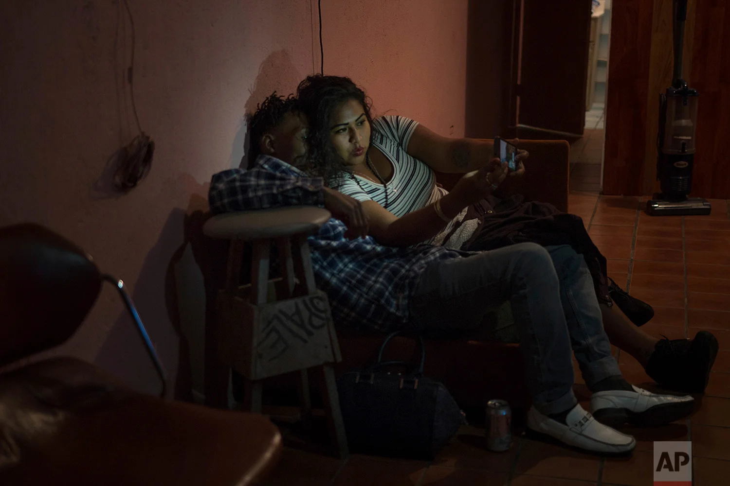 Adriana, from Mexico, and Etienne, from Haiti, take a selfie during a party in Tijuana, Mexico, Feb. 25, 2018. (AP Photo/Emilio Espejel)