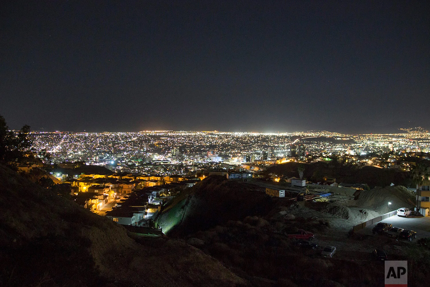 Lights shine over the city of Tijuana, Mexico, Feb. 21, 2018. San Diego's office towers can be seen in the distance. (AP Photo/Emilio Espejel)