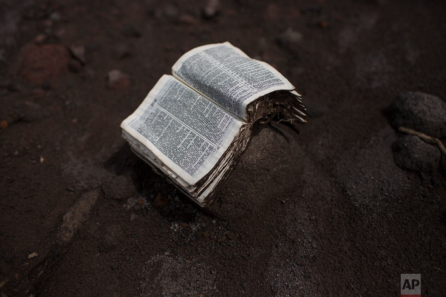  This June 8, 2018 photo shows a salvaged Bible placed on a rock, opened to the Book of Job, in San Miguel Los Lotes, Guatemala. (AP Photo/Rodrigo Abd) 