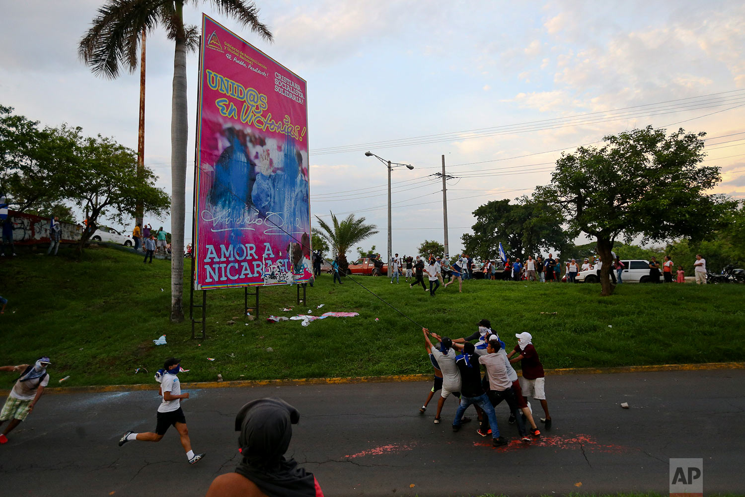 In this May 20, 2018 photo, anti-government protesters work to pull down a government billboard announcing the Spanish message "United in victory! Love for Nicaragua," in Managua, Nicaragua. (AP Photo/Esteban Felix) 