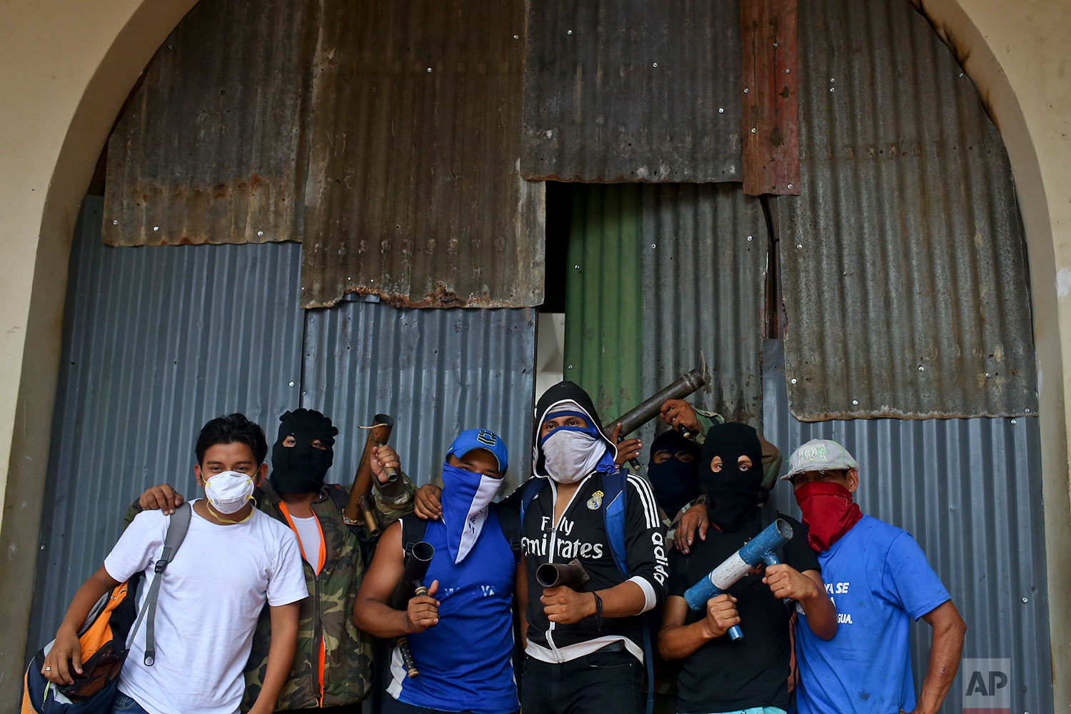  In this May 28, 2018 photo, masked protesters pose for a group photo holding their homemade mortars, outside a shopping center with a store covered by metal sheeting to protect it from looting, in Masaya, Nicaragua. (AP Photo/Esteban Felix) 