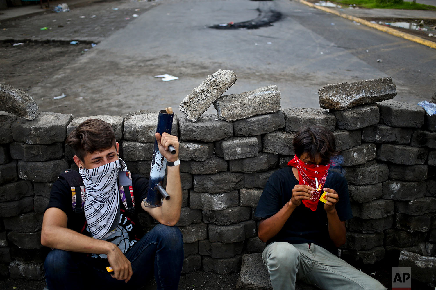  In this May 31, 2018 photo, young anti-government protesters squat behind a roadblock they set up near the Supreme Electoral Council, one holding his homemade mortar in Managua, Nicaragua. (AP Photo/Esteban Felix) 