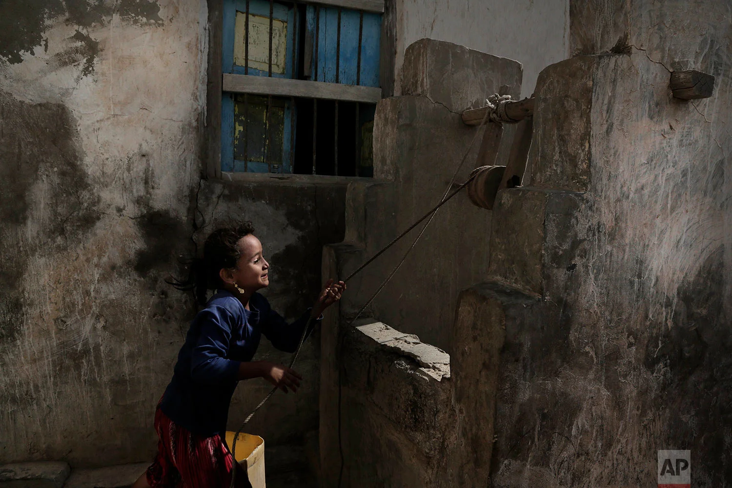 A girl pulls water from a well in the home of Ahmed al-Kawkabani, leader of the southern resistance unit in Hodeida, in al-Khoukha, Yemen. (AP Photo/Nariman El-Mofty)