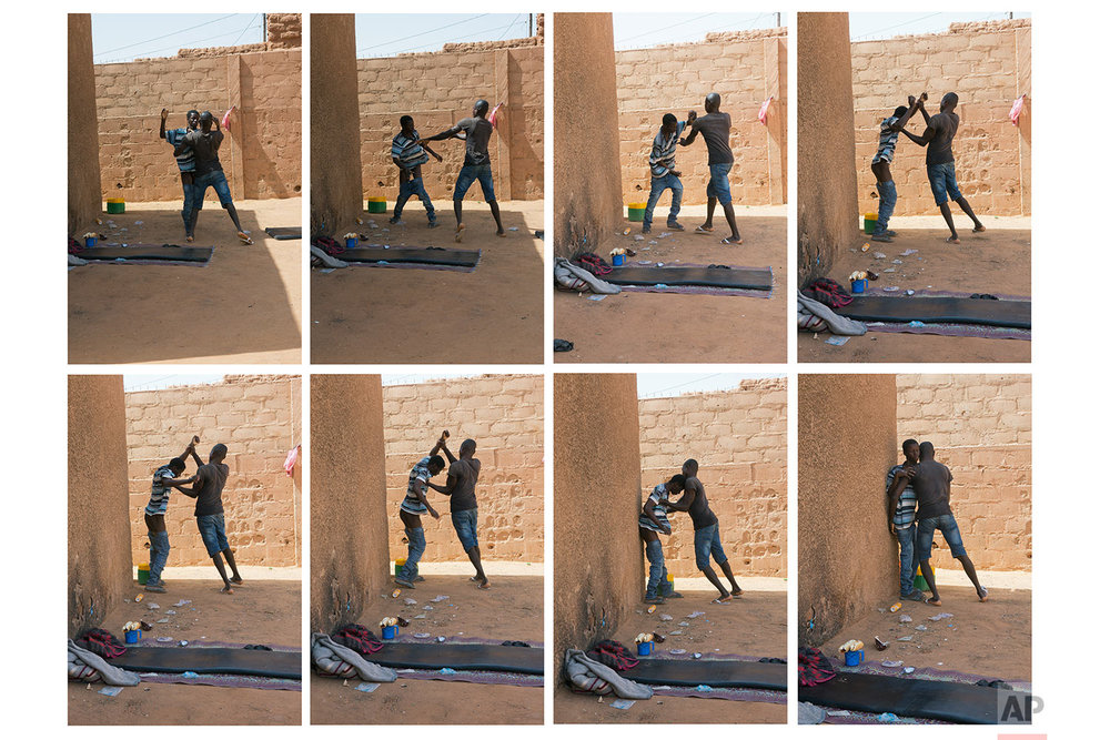  A young migrant who has been expelled from Algeria is restrained by others after he attempted to strip naked in a transit center in Arlit, Niger, on June 2, 2018. (AP Photo/Jerome Delay) 