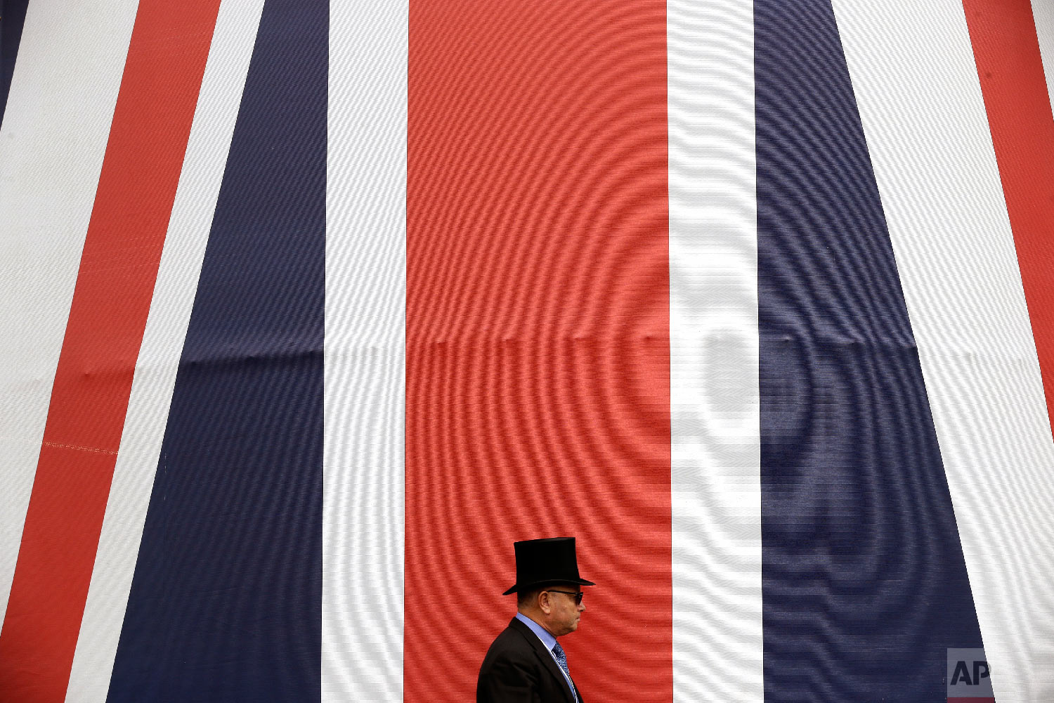  A racegoer walks past a huge British flag during the second day of the Royal Ascot horse race meeting in Ascot, England, Wednesday, June 20, 2018. (AP Photo/Tim Ireland) 