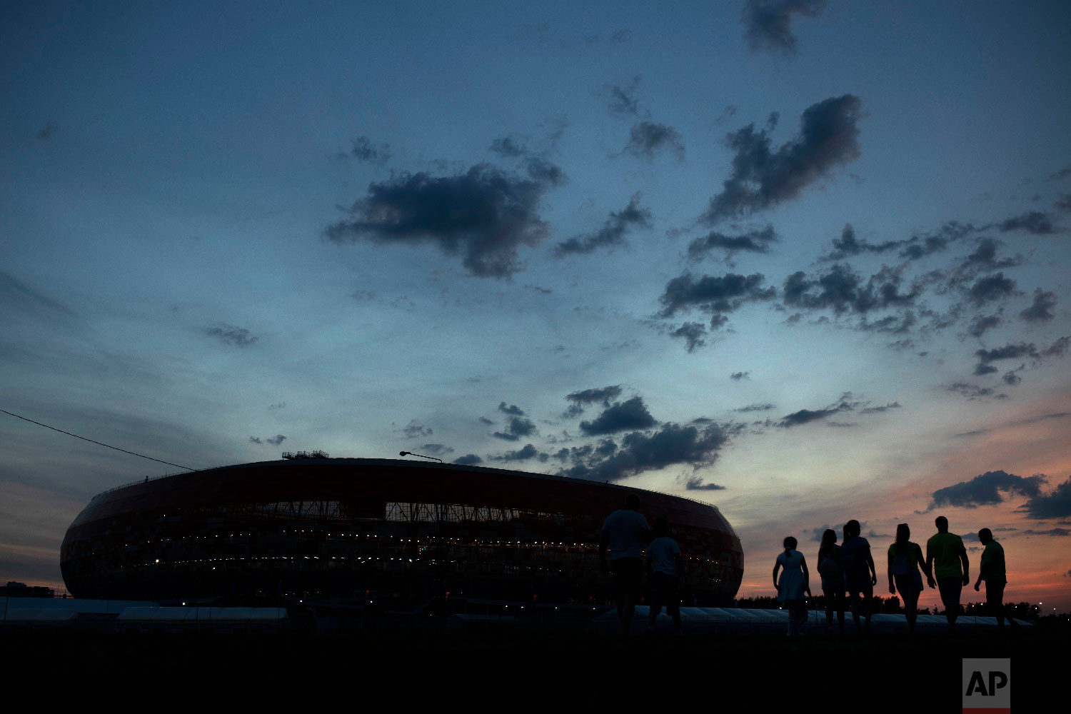  People walk next to the Mordovia Arena stadium as the sun sets at the 2018 soccer World Cup in Saransk, Russia on June 24, 2018. (AP Photo/Francisco Seco) 