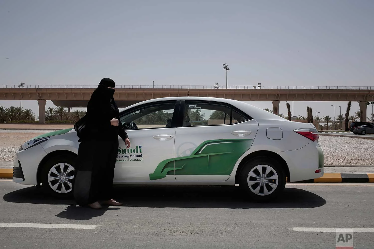 In this June 23, 2018 photo, 27-year old driving instructor Mabkhoutah al-Mari stands next to a test drivers car at the Saudi Driving School inside Princess Nora University in Saudi Arabia. (AP Photo/Nariman El-Mofty)