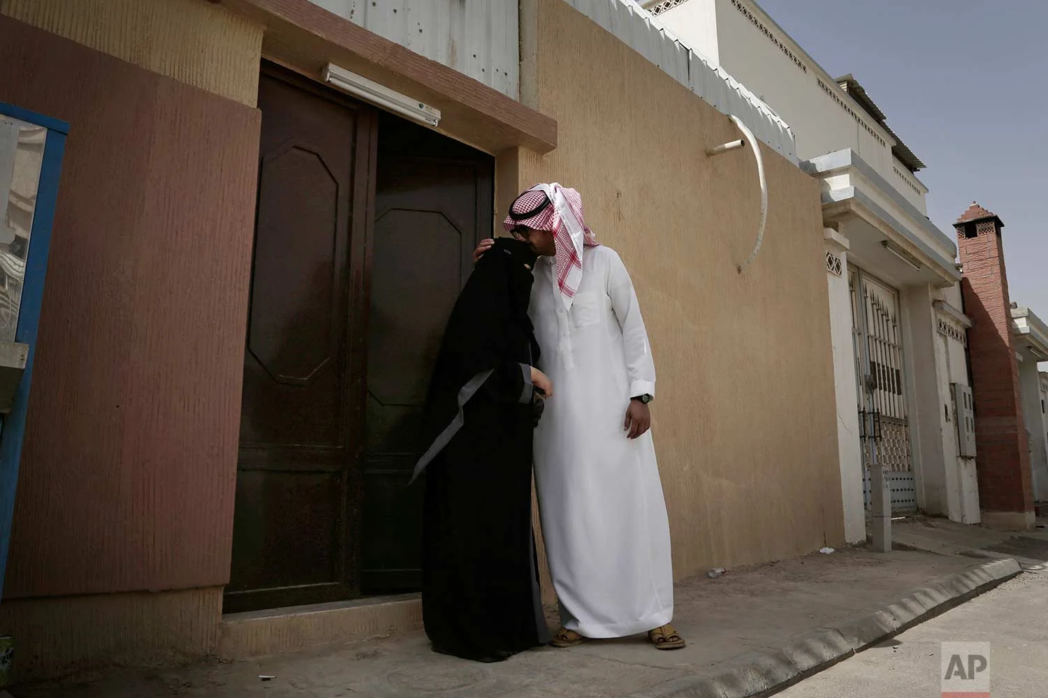 In this Sunday, June 24, 2018 photo, the brother of 27-year old Mabkhoutah al-Mari, kisses her forehead before she drives to work for the first time in Riyadh, Saudi Arabia. (AP Photo/Nariman El-Mofty)