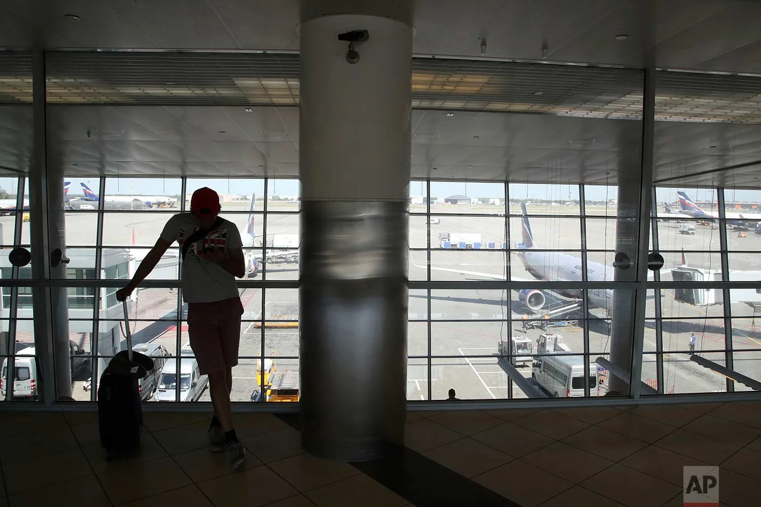 In this Friday, June 22, 2018 photo, a soccer fan wearing a T-shirt with the British flag checks his cellphone after a flight at Sheremetyevo International Airport, in Moscow, Russia. (AP Photo/Thanassis Stavrakis)