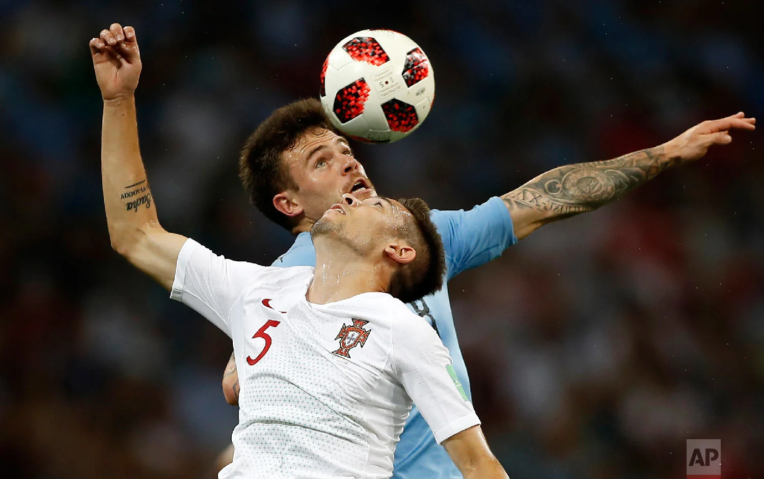 Portugal's Raphael Guerreiro and Uruguay's Nahitan Nandez, top, challenge for the ball during the round of 16 match between Uruguay and Portugal at the 2018 soccer World Cup at the Fisht Stadium in Sochi, Russia, Saturday, June 30, 2018. (AP Photo/Francisco Seco)