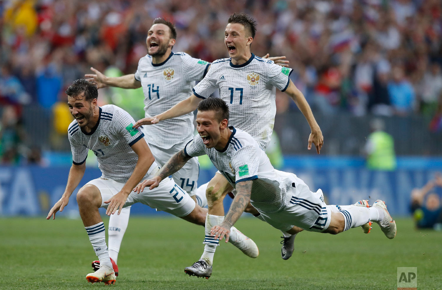 Russia's Fyodor Smolov, right, dives as he celebrates with teammates after Russia defeated Spain in a penalty shoot out during the round of 16 match between Spain and Russia at the 2018 soccer World Cup at the Luzhniki Stadium in Moscow, Russia, Sunday, July 1, 2018. (AP Photo/Manu Fernandez)