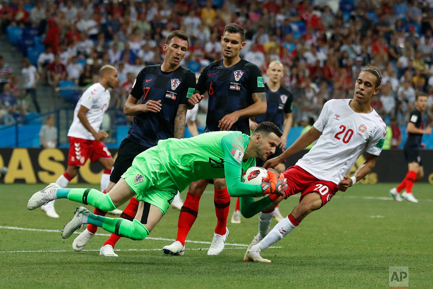 Croatia goalkeeper Danijel Subasic, front, secures the ball next to Denmark's Yussuf Yurary Poulsen, right, during the round of 16 match between Croatia and Denmark at the 2018 soccer World Cup in the Nizhny Novgorod Stadium, in Nizhny Novgorod, Russia, Sunday, July 1, 2018. (AP Photo/Darko Bandic)