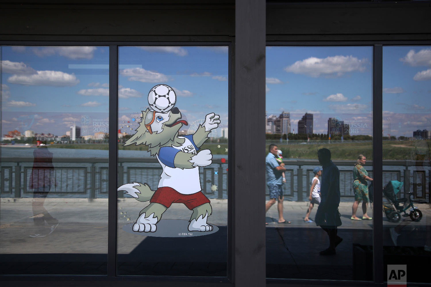  A volunteer, left, walks inside the Fan ID center as pedestrians are reflected in a window as they walk along the banks of the Volga river during the 2018 soccer World Cup in Kazan, Russia on June 29, 2018. (AP Photo/Thanassis Stavrakis) 