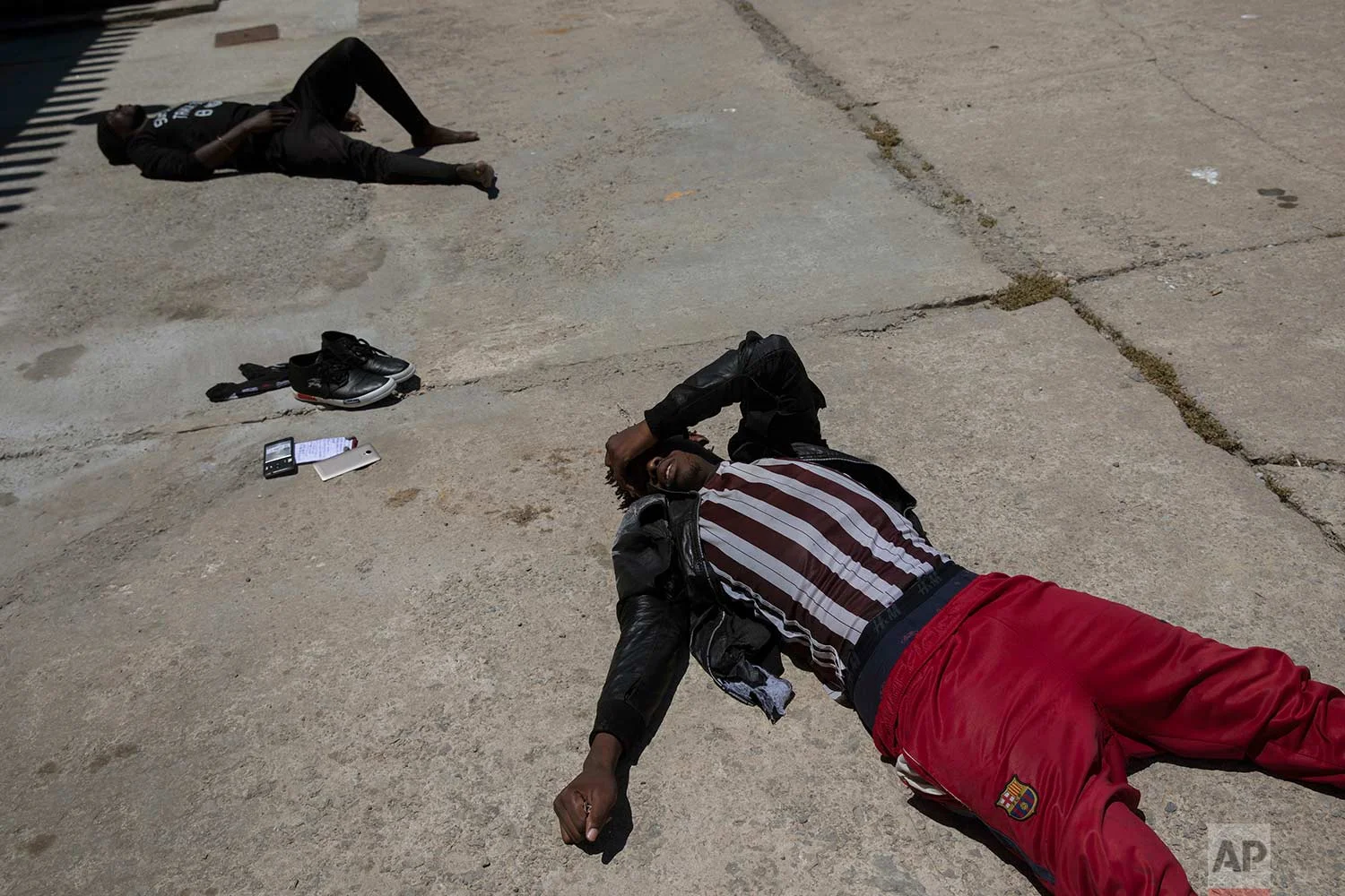 Migrants lay on the ground exhausted at the port of Tarifa, southern Spain, after being rescued by Spain's Maritime Rescue Service in the Strait of Gibraltar, Friday, June. 29, 2018. European Union leaders declared victory Friday, claiming to have set aside major differences over how best to handle migrant arrivals as they commissioned new plans to screen people in North Africa for eligibility to enter Europe. (AP Photo/Emilio Morenatti)