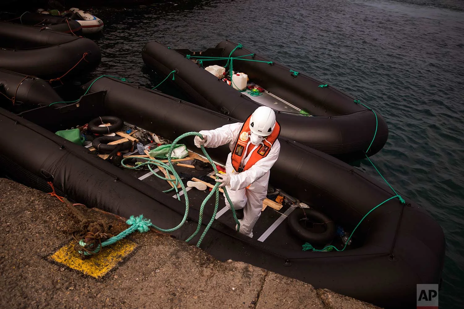 In this Wednesday, June 27, 2018 photo, a rescue member moors a rubber dinghy used by migrants, at the port of Tarifa, southern Spain. The route from northern Africa into Spain has become the most popular for those seeking a better life in Europe, testing Spain’s response networks as the migration debate re-emerges in the region. (AP Photo/Emilio Morenatti)