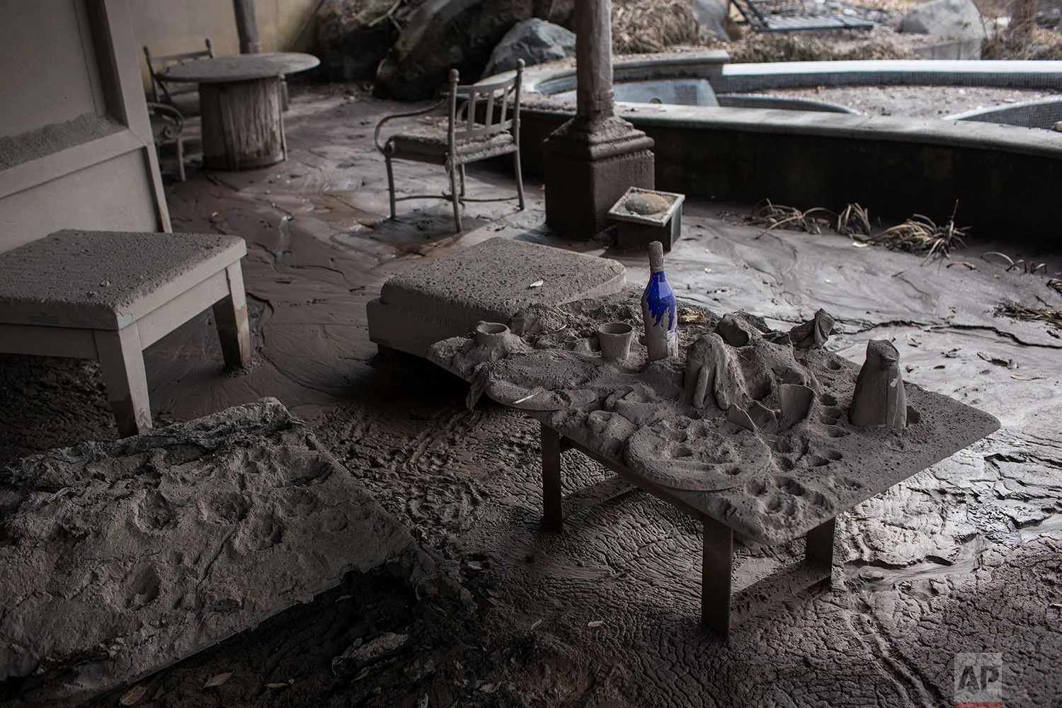 A table with plates and bottles sits blanketed in volcanic ash at the golf resort. San Miguel Los Lotes. June 16, 2018. (AP Photo/Rodrigo Abd)