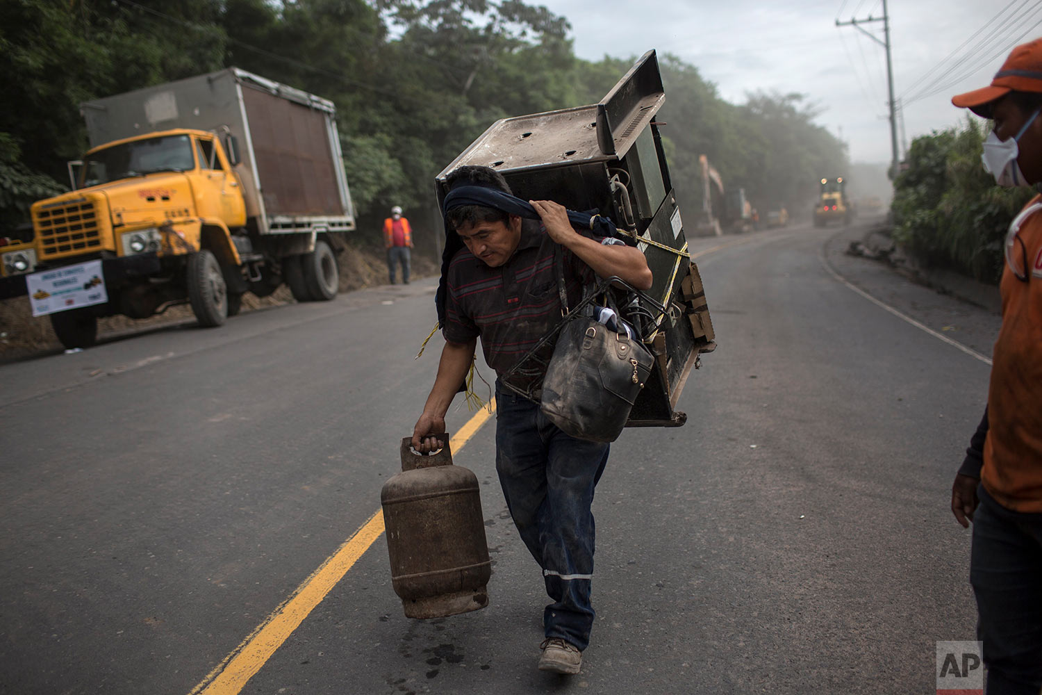  A resident carries a stove and gas can recovered from his volcano-destroyed home, following the eruption of the Volcano of Fire in San Miguel Los Lotes, Guatemala, June 10, 2018. (AP Photo/Rodrigo Abd) 