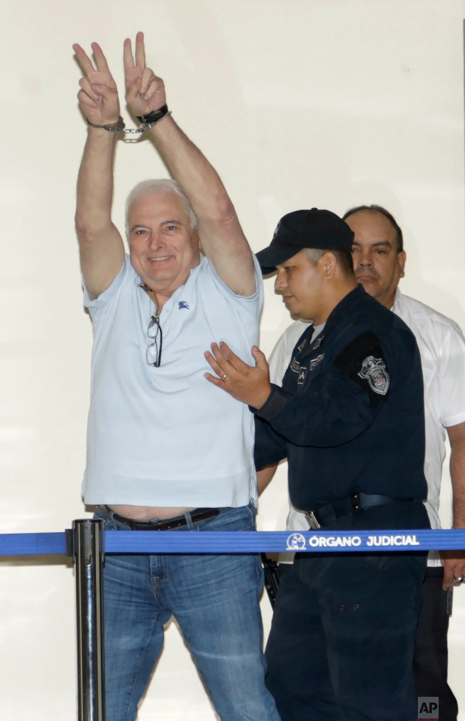 Former Panamanian President Ricardo Martinelli gestures victory from his handcuffs while escorted away from his hearing at the Supreme Court in Panama City, June 11, 2018. Martinelli returned to Panama to face political espionage and embezzlement charges after being extradited from the U.S. (AP Photo/Arnulfo Franco)