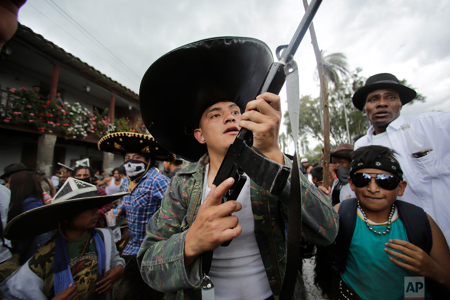  Indigenous men in costume, one holding a mock gun made of wood, dance to the rhythm of the monotonous tune of San Juanito, as groups from different communities compete to occupy the main plaza during the Sun Festival in Cotacachi, Ecuador, June 24, 