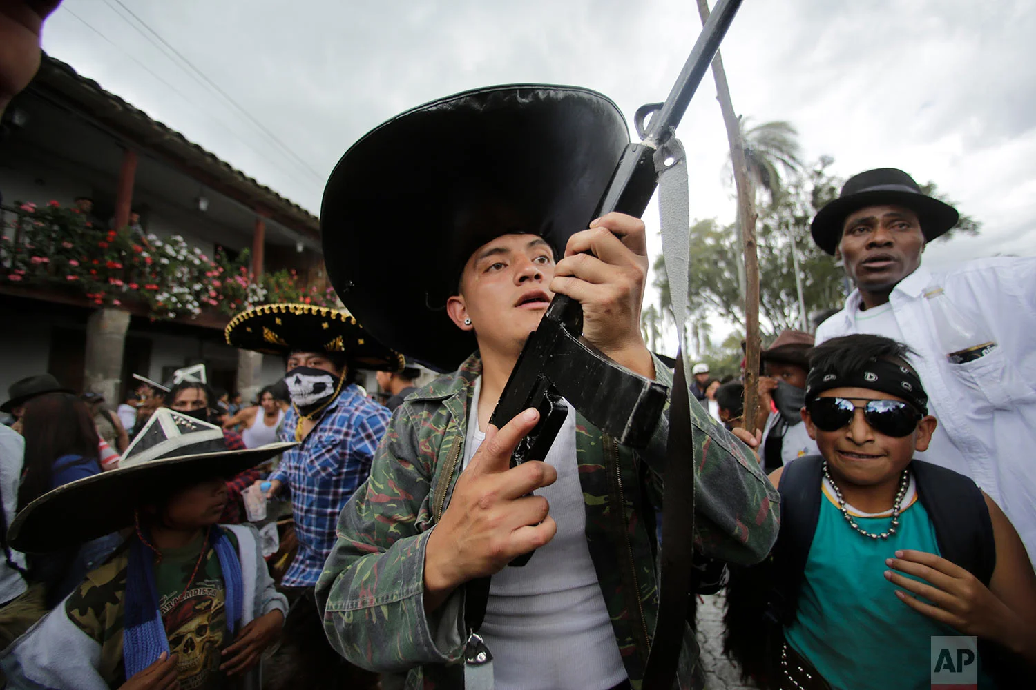 Indigenous men in costume, one holding a mock gun made of wood, dance to the rhythm of the monotonous tune of San Juanito, as groups from different communities compete to occupy the main plaza during the Sun Festival in Cotacachi, Ecuador, June 24, 2018. Across the Andes, from the tip of Argentina as far north as Colombia, indigenous communities are gathering for the southern hemisphere's winter solstice to honor the ancient sun god. (AP Photo/Dolores Ochoa)