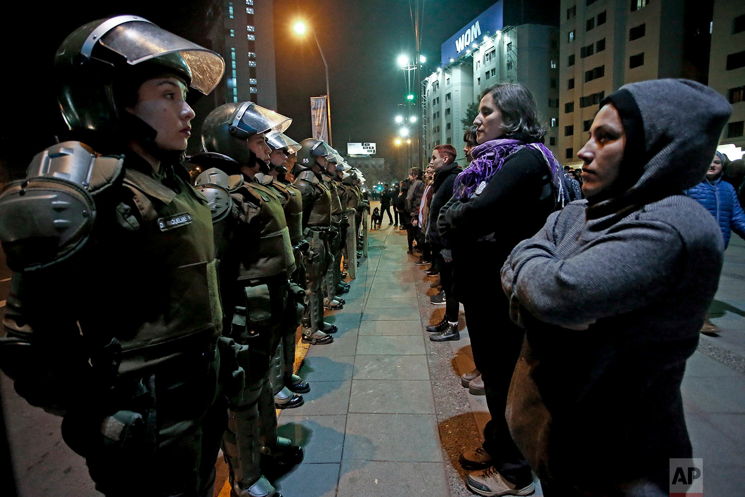  In this June 1, 2018 photo, women face a line of policewomen at the start of a feminist march in Santiago, Chile. 
A seemingly light ruling against a university professor for sexual harassment outraged women across the country who demanded a stronge