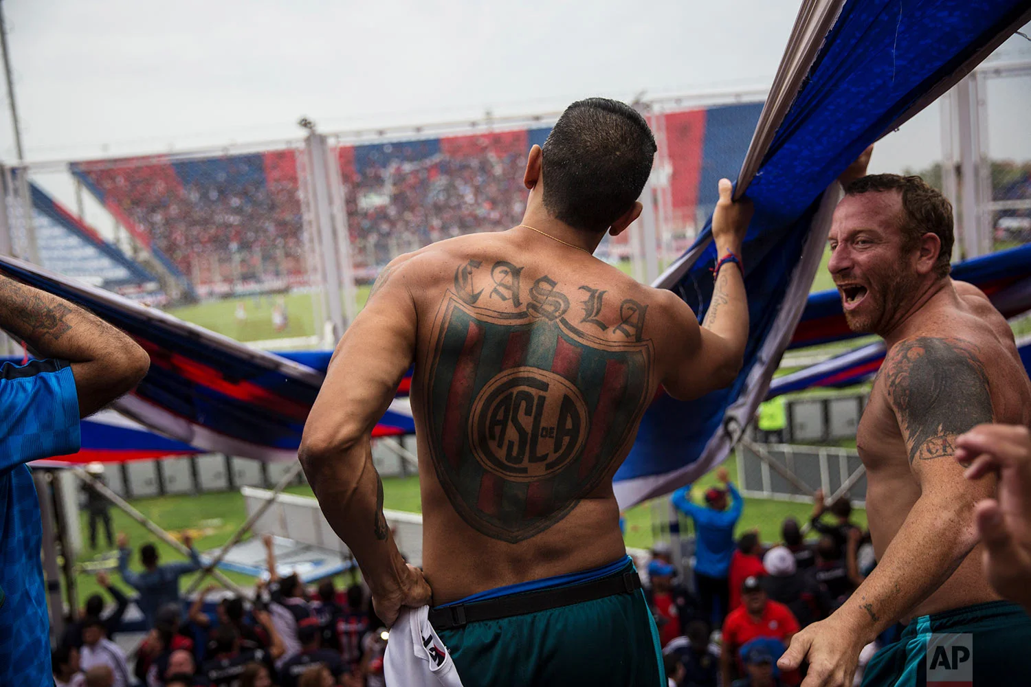 In this April 8, 2018 photo published in June, San Lorenzo soccer fans who are part of the team's most militant fan base, coined "La Butteler," sing and dance in the grandstand during a match against Godoy Cruz in Buenos Aires, Argentina. (AP Photo/Rodrigo Abd)