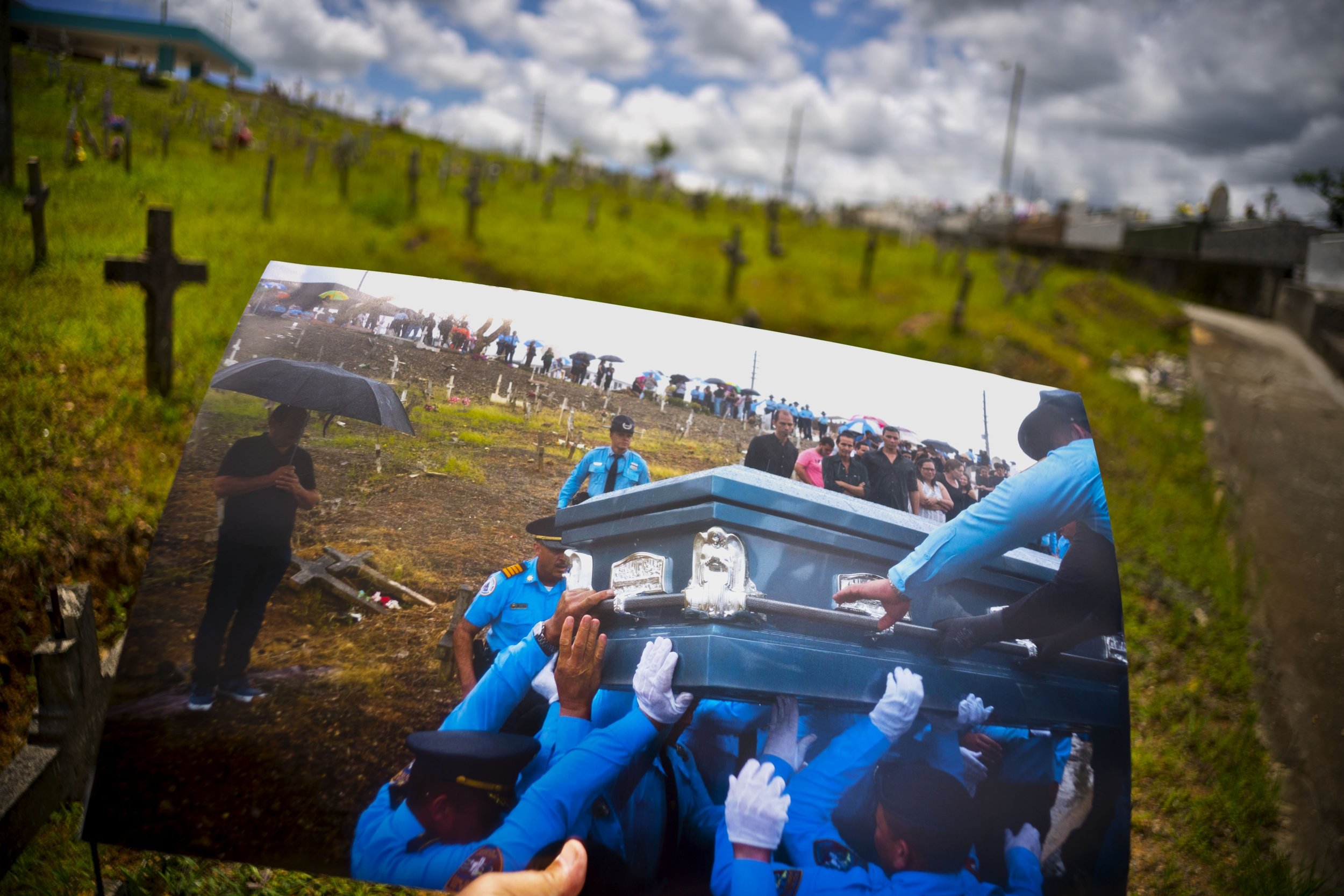  A printed photo taken on Sept. 29, 2017 showing police lifting the coffin of officer Luis Angel Gonzalez Lorenzo, who was killed during the passage of Hurricane Maria when he tried to cross a river in his car, is shown at the same cemetery in Aguada